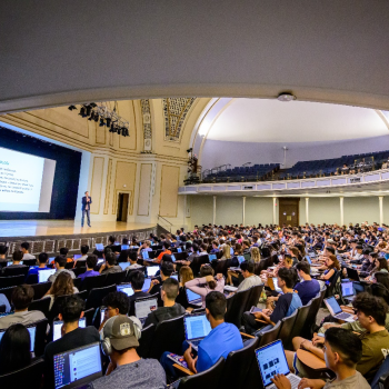A professor lecturing in front of a large room of students