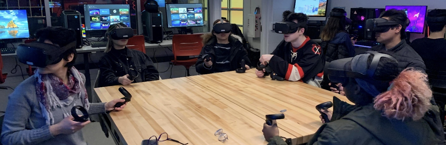 students wearing VR headsets sitting around a large square table in the Innovation Studio