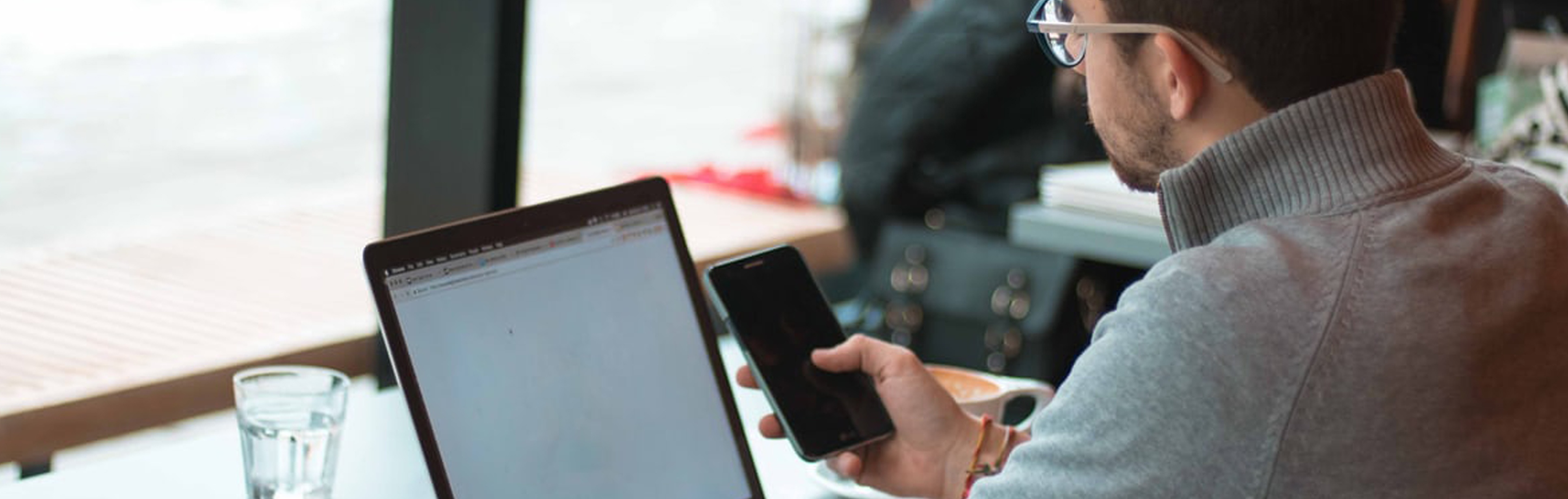 person-looking-at-their-phone-and-laptop